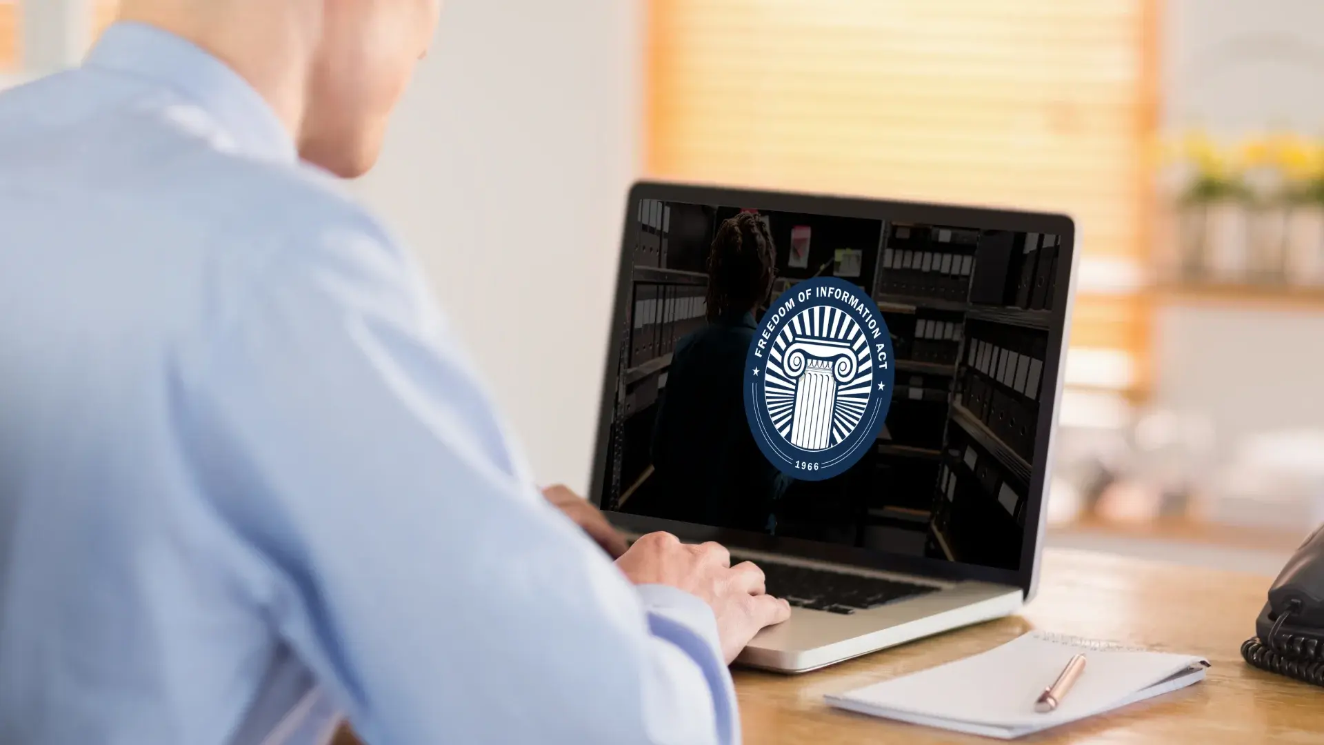 Person viewing Freedom of Information Act seal on a laptop while preparing digital records