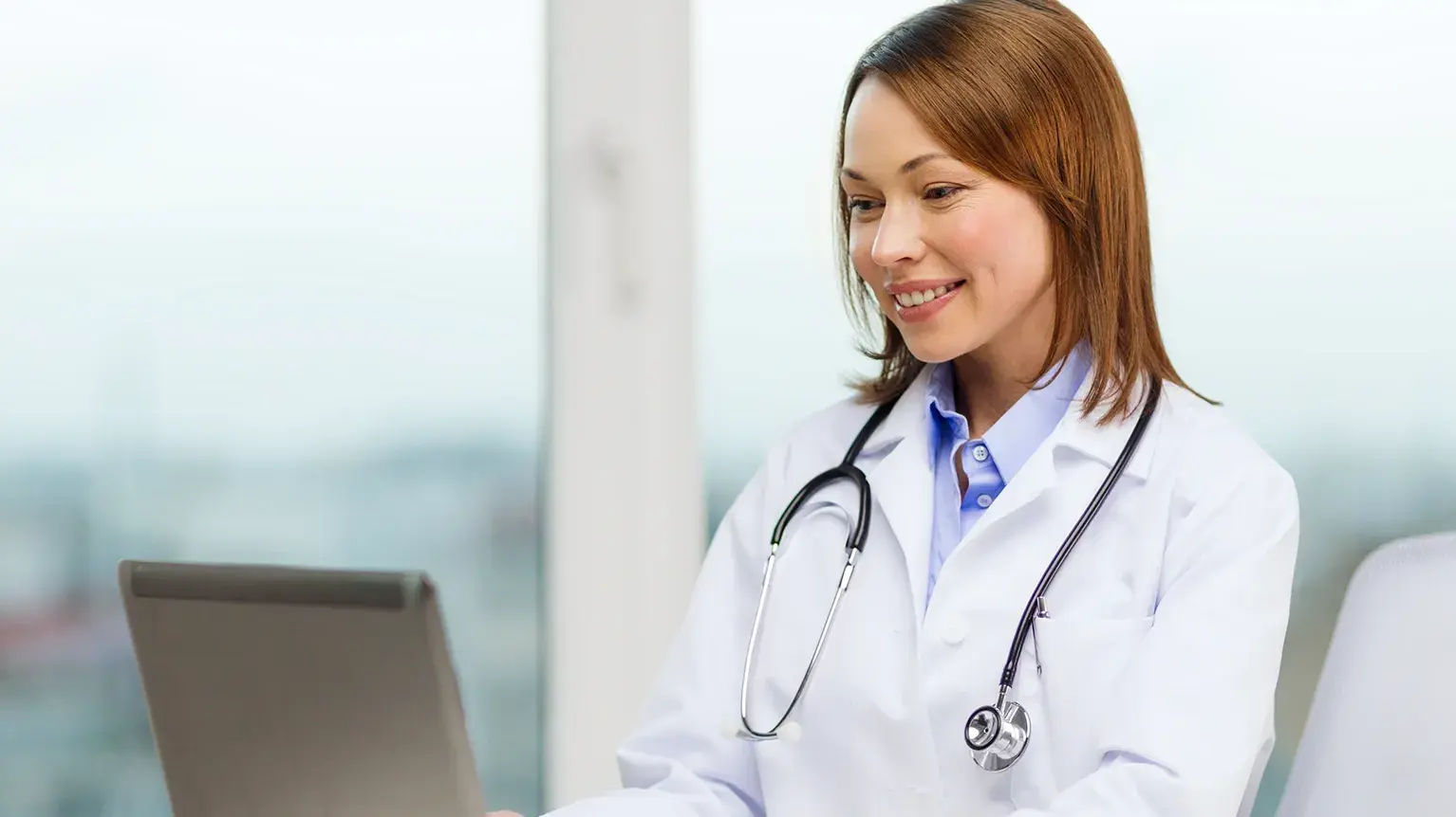 Female healthcare professional reviewing digital records on laptop in clinical setting